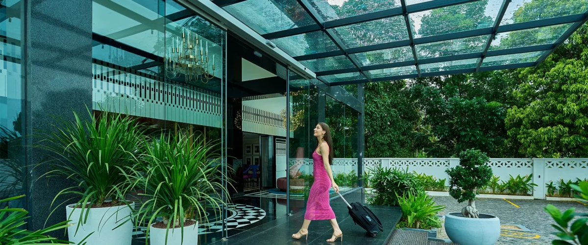 Woman entering Noah Sky Suites hotel with luggage trolley in Nedumbassery